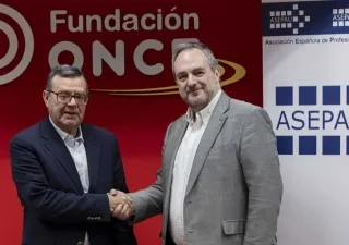 Los dos representantes sellando el acuerdo frente a los logos de las empresa