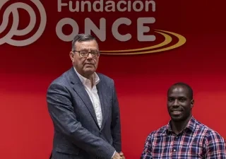 Amadou y Donoso estechándose la mano delante del logo de Fundación ONCE