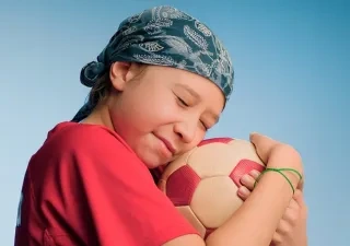 Niño con cáncer infantil jugando con una pelota