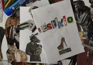 Alt text:  Mesa de trabajo con materiales para un taller de collage. En el centro, varias hojas blancas muestran composiciones realizadas con recortes de revistas; una de ellas forma la palabra “BESTIARIO” con letras de distintos colores y tamaños. Alrededor se ven imágenes recortadas de obras de arte, esculturas, animales y figuras humanas, junto con lápices de colores, pegamento en barra y unas tijeras rosas. La escena documenta un proceso creativo de creación artística mediante collage.