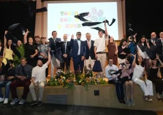 Todos los alumnos graduados posando en el escenario