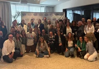 Foto de grupo de familias, profesionales y personas con discapacidad reunidas en una sala, posando juntas tras el taller “Adolescencia, familia y discapacidad” de la Fundación Kike Osborne en Valencia, con un photocall de la Fundación al fondo.