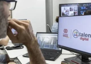 Un hombre con gafas mirando a la pantalla de un ordenador donde sale el logo de por talento digital y fundación once