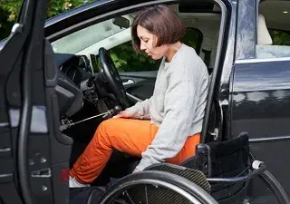 Una persona en silla de ruedas saliendo de su coche adaptado y aparcado en una plaza reservada para el colectivo (Fuente: La Europa Social/Olena Yakobchuk/shutterstock.com)