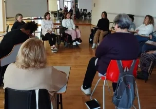 Las mujeres participantes del programa reunidas en una sala con todas sentadas haciendo un círculo para hablar