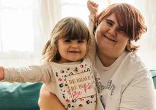 Una mare junto a su hija sentadas en el sofá