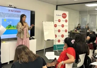 Dos profesores dando una explicación a sus alumnas, que están sentadas en sus pupitres