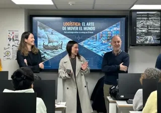 Varios formadores del taller impartiendo indicaciones frente a los alumnos, con el proyector de fondo presentando una diapositiva