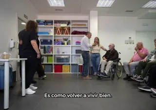 Personas diversas en una sala, aparecen sentadas.