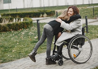 Mujer en silla de ruedas abrazando a una niña, que podría ser su hija (Fuente: Servimedia)
