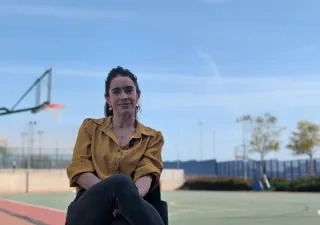 Una de las impulsoras del estudio, posando a cámara sentada en una pista de atletismo y baloncesto de fondo.