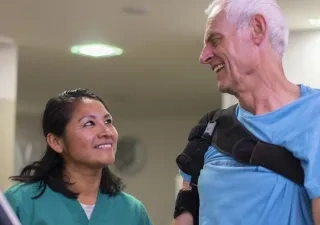 Un señor mayor siendo tratado por una mujer rehabilitadora