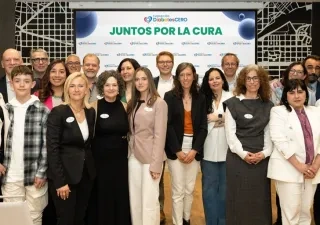 Veinte personas posando para la foto junto delante de la pantalla digital donde se proyectan diapositivas del encuentro