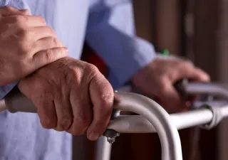 Primer plano de las manos de un hombre mayor sosteniendo un andador