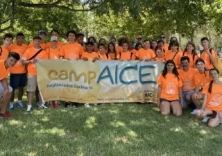 Posado de todos los participantes del campamento, sujetando una bandera con el logo CampAICE