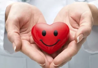 medico sosteniendo un corazón de juguete con una sonrisa dibujada