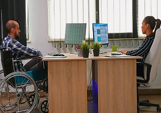 Una persona en silla de ruedas trabaja en una oficina junto a otra compañera (Fuente: Servimedia)