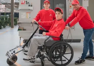 En la imagen se puede ver a los dos alumnos y al profesor, uno de ellos probando el proyecto en una silla de ruedas
