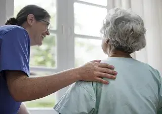 Una enfermera atendiendo a una anciana (Fuente: Servimedia)