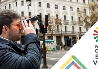 Cartel de la Fundación ONCE Baja Visión con el logo de la fundación a la derecha y un hombre en la calle mirando con prismáticos a la izquierda