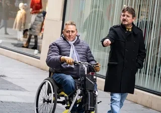 Un asistente personal al lado de un hombre en silla de ruedas