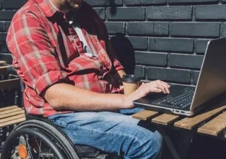 persona en silla de ruedas con discapacidad usando el portátil