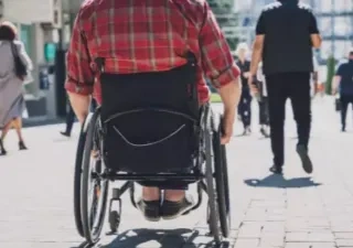 persona en silla de ruedas caminando por la vía pública