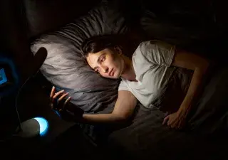 mujer mirando el movil por la noche en la cama a causa del insomnio