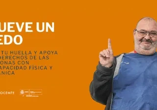 Hombre sonriente levantando el dedo índice frente a un fondo naranja en la campaña “Mueve un Dedo” de COCEMFE.