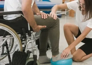 Fisioterapeuta con una persona con discapacidad realizando un tratamiento de rehabilitación