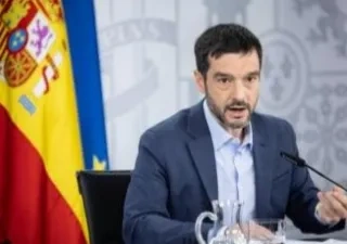 Pablo Bustinduy, Ministro de Derechos Sociales, en una rueda de prensa oficial. Detrás tiene la bandera de la UE y de España