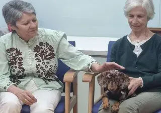 Dos personas mayores junto a un perro en una sesión de terapia asistida con animales (Fuente: Neurovida)