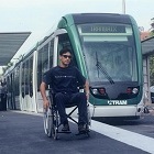 Persona en silla de ruedas al lado del tranvia TRAM