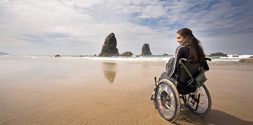 persona en silla de ruedas en la playa, pensando en la vuelta de vacaciones